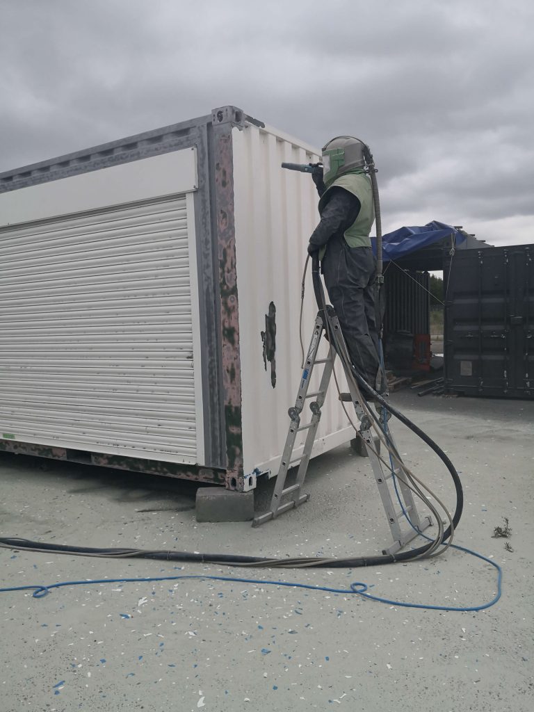 Sand blasting shipping container conversion ahead of new paint application